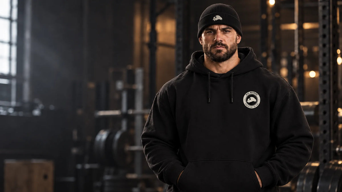 Athlete in a black Kill Nothing club crest hoodie and bison beanie in a dark gym